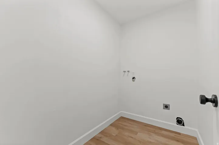 Utility area featuring wood-finish flooring, white baseboards, and bright white walls