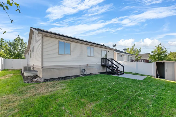 Rear exterior featuring white siding, a dark wood-finish deck with stairs, and a white privacy fence