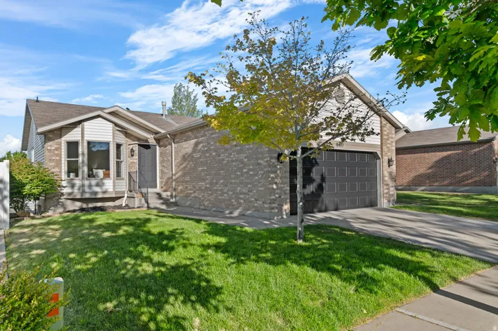 Brick and siding exterior featuring a bay window, attached garage with a paneled door, and a concrete driveway