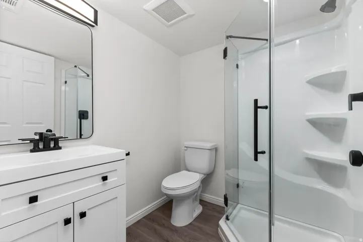 Contemporary bathroom featuring a white vanity with integrated sink, matte black faucet, and a sleek rectangular mirror