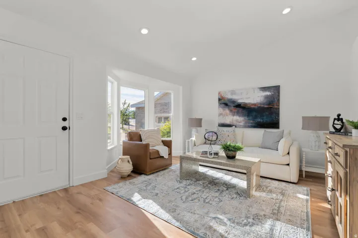 Bright living area featuring wood-finish flooring, recessed lighting, and a bay window with multiple panes