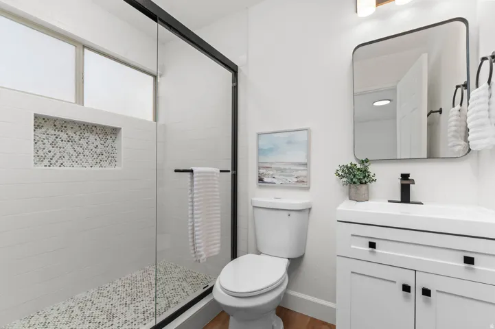 Contemporary bathroom featuring a walk-in shower with mosaic tile niche, a sleek vanity with a rectangular sink, and matte black fixtures