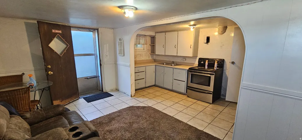 Compact kitchen space featuring white cabinetry, a stainless steel range, and tile flooring