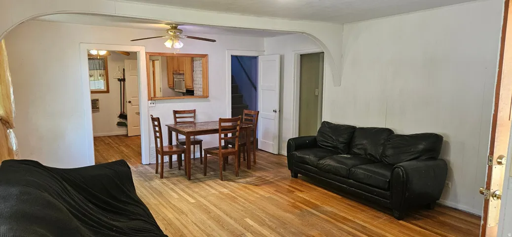 Hardwood flooring extends throughout the living and dining areas, featuring an arched doorway and a pass-through window to the kitchen