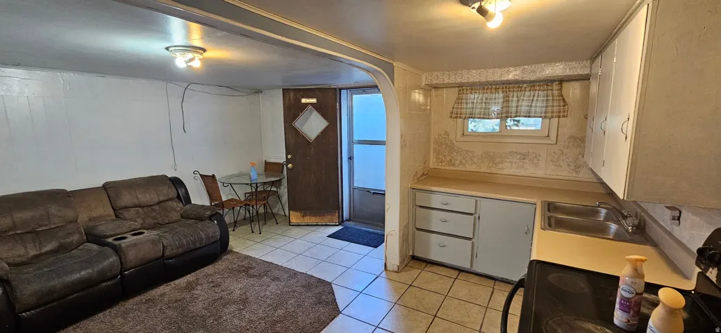 Kitchenette area featuring a double basin sink, white cabinetry, and a window above the countertop