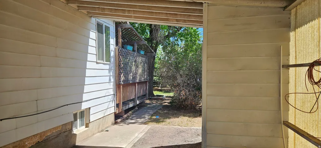 Covered outdoor passage with a concrete walkway, featuring exterior siding, a window, and partial foundation exposure