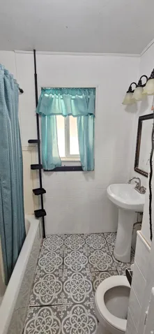 Bathroom featuring patterned floor tiles, white pedestal sink, and a window