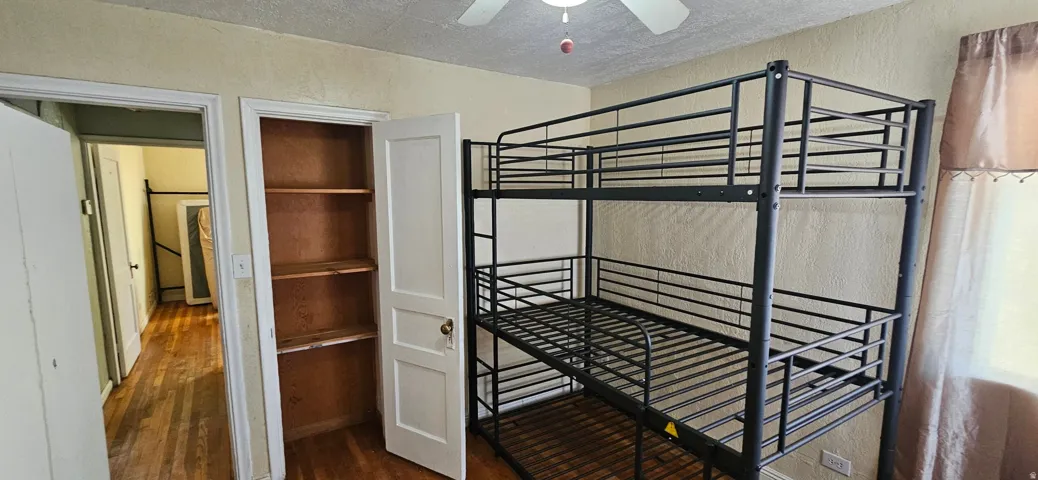 Room featuring wood-finish flooring, a ceiling fan, and built-in shelving