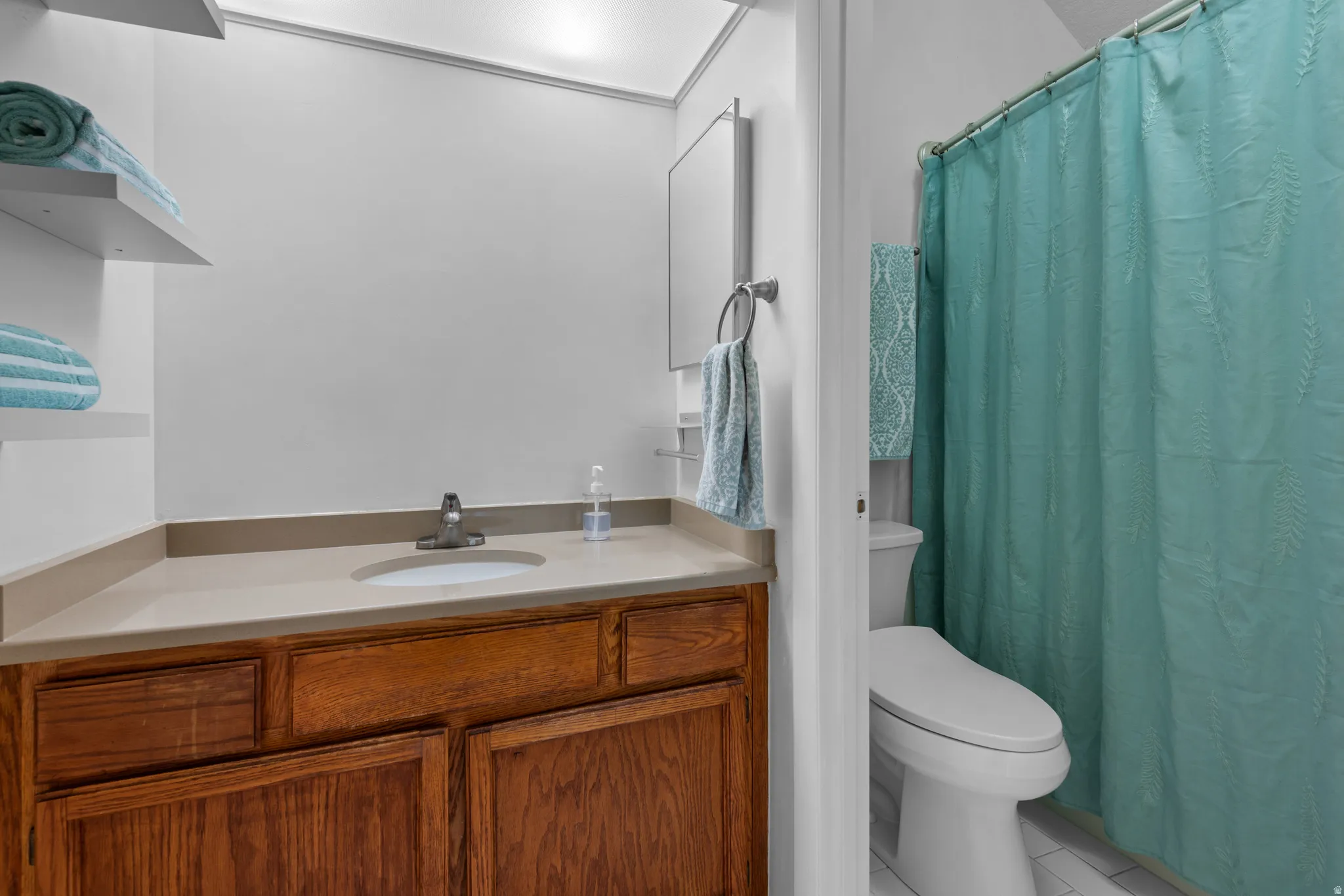 Bathroom featuring a wood-finish vanity with an integrated sink, a light-toned countertop, and a wall-mounted medicine cabinet