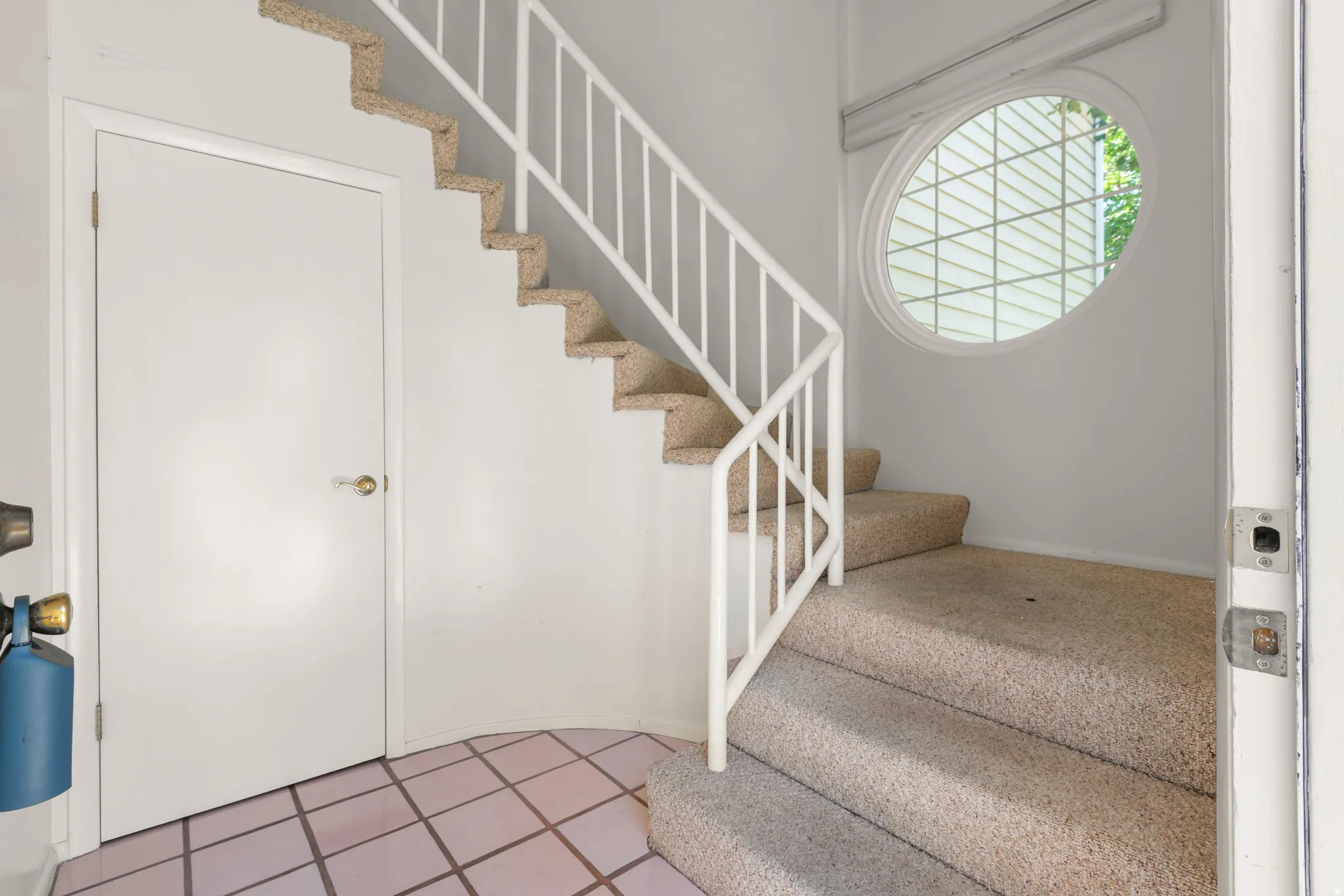 Carpeted staircase with white metal railing and a distinct circular window