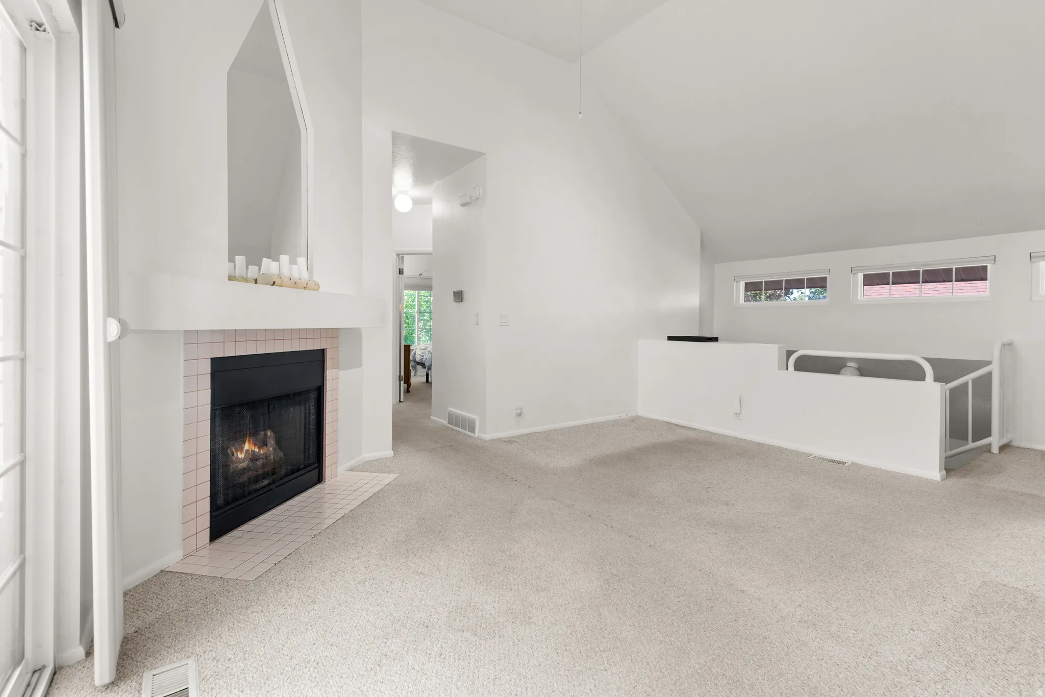 Living space featuring a fireplace with a light-tiled surround, a mantel, and an architectural alcove