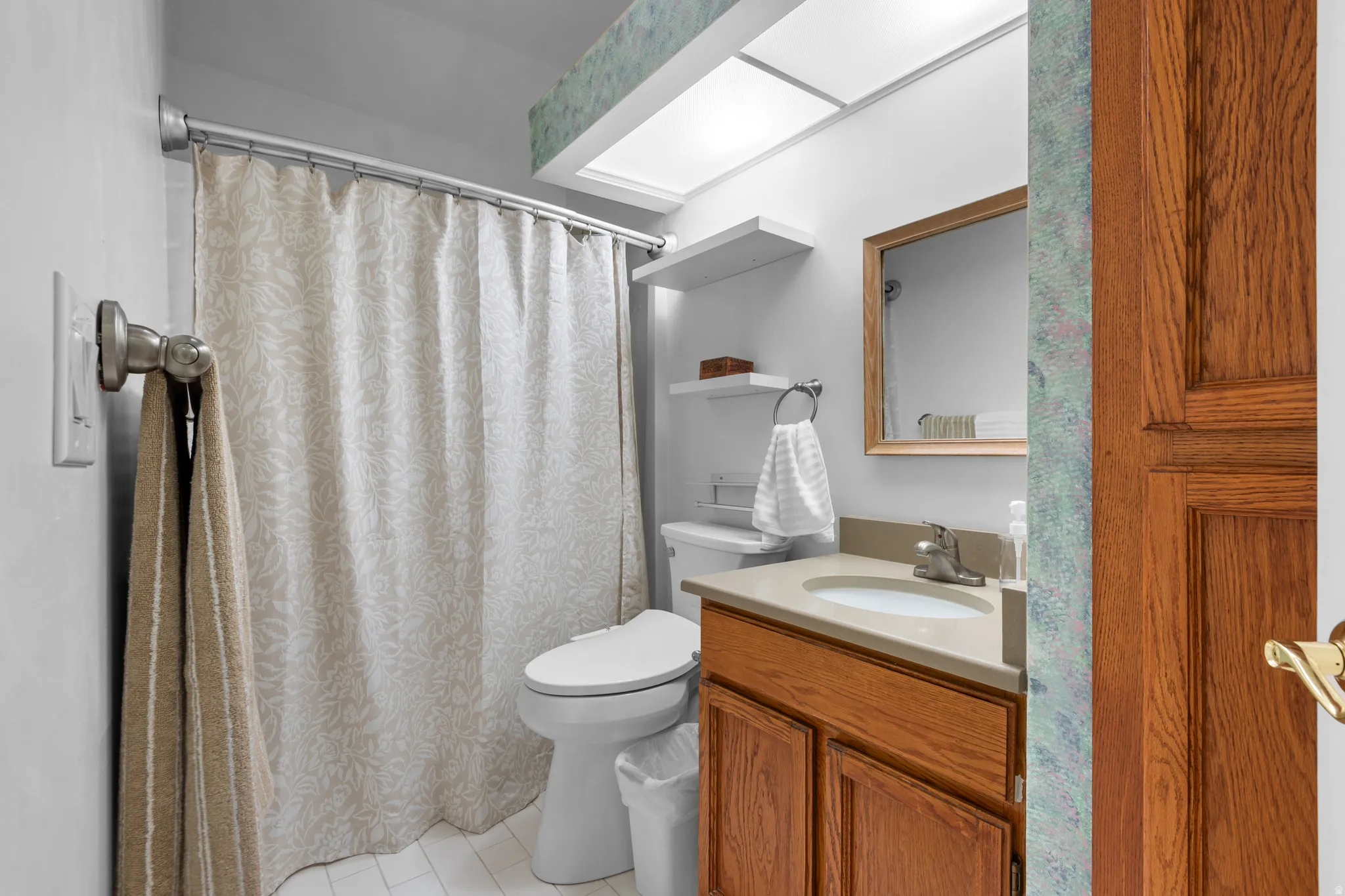 Bathroom featuring a vanity with wood-finish cabinetry, a single-basin sink, and a light-toned countertop