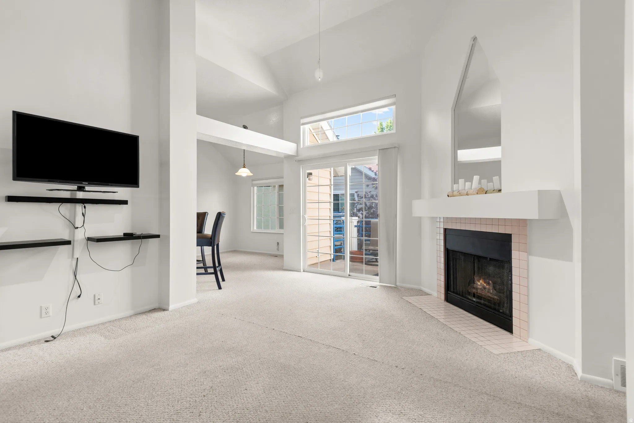Living area featuring a fireplace with a tiled surround, a white mantel, and a mirrored accent