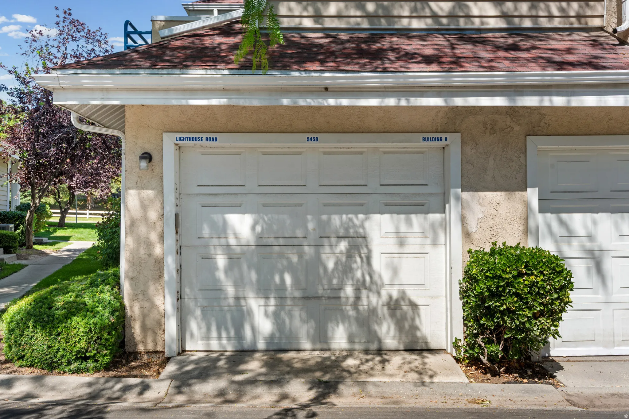 Single-car garage with panel-style door, stucco exterior, and red tile roofing