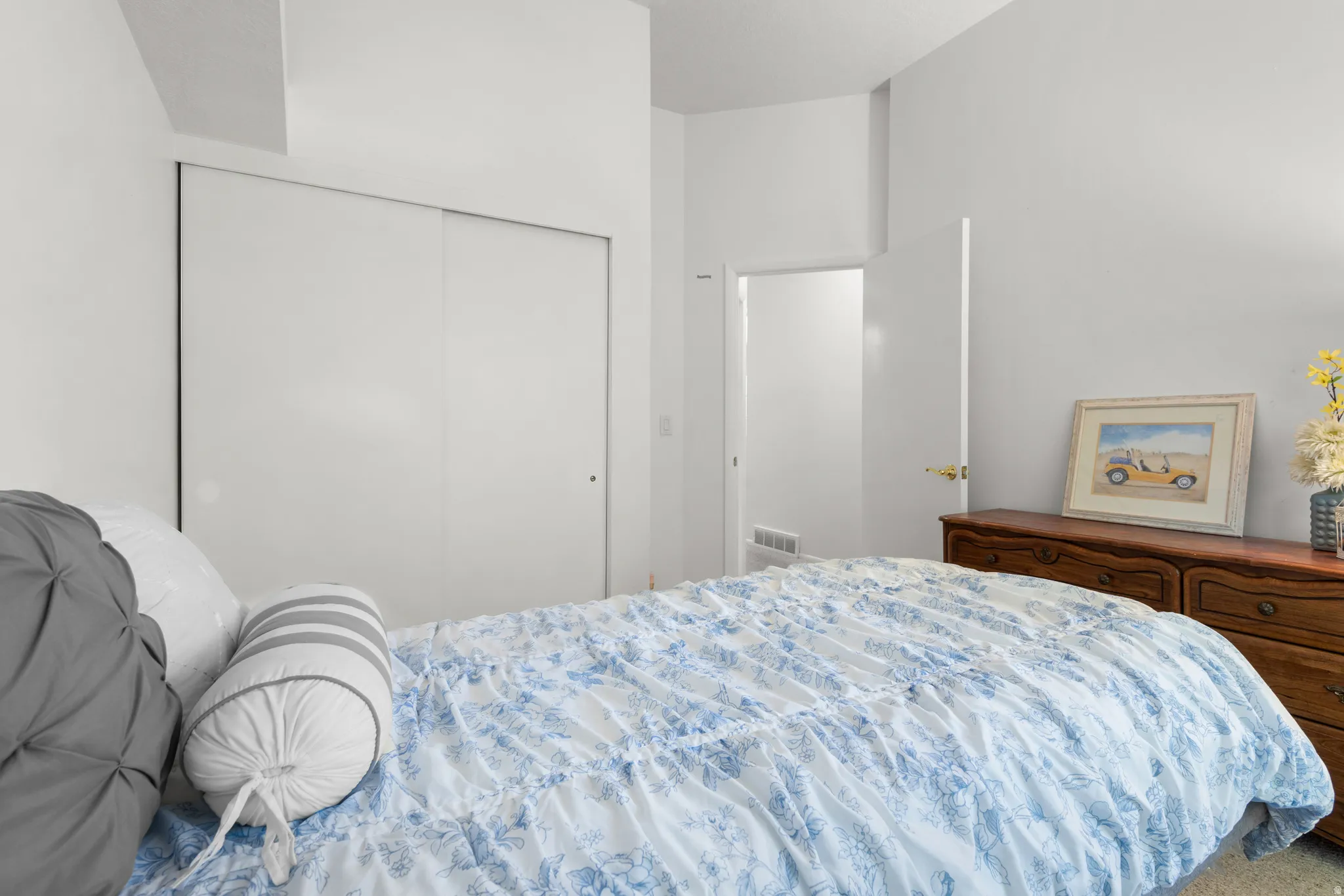 Bedroom featuring a built-in sliding door closet and a wall-mounted register