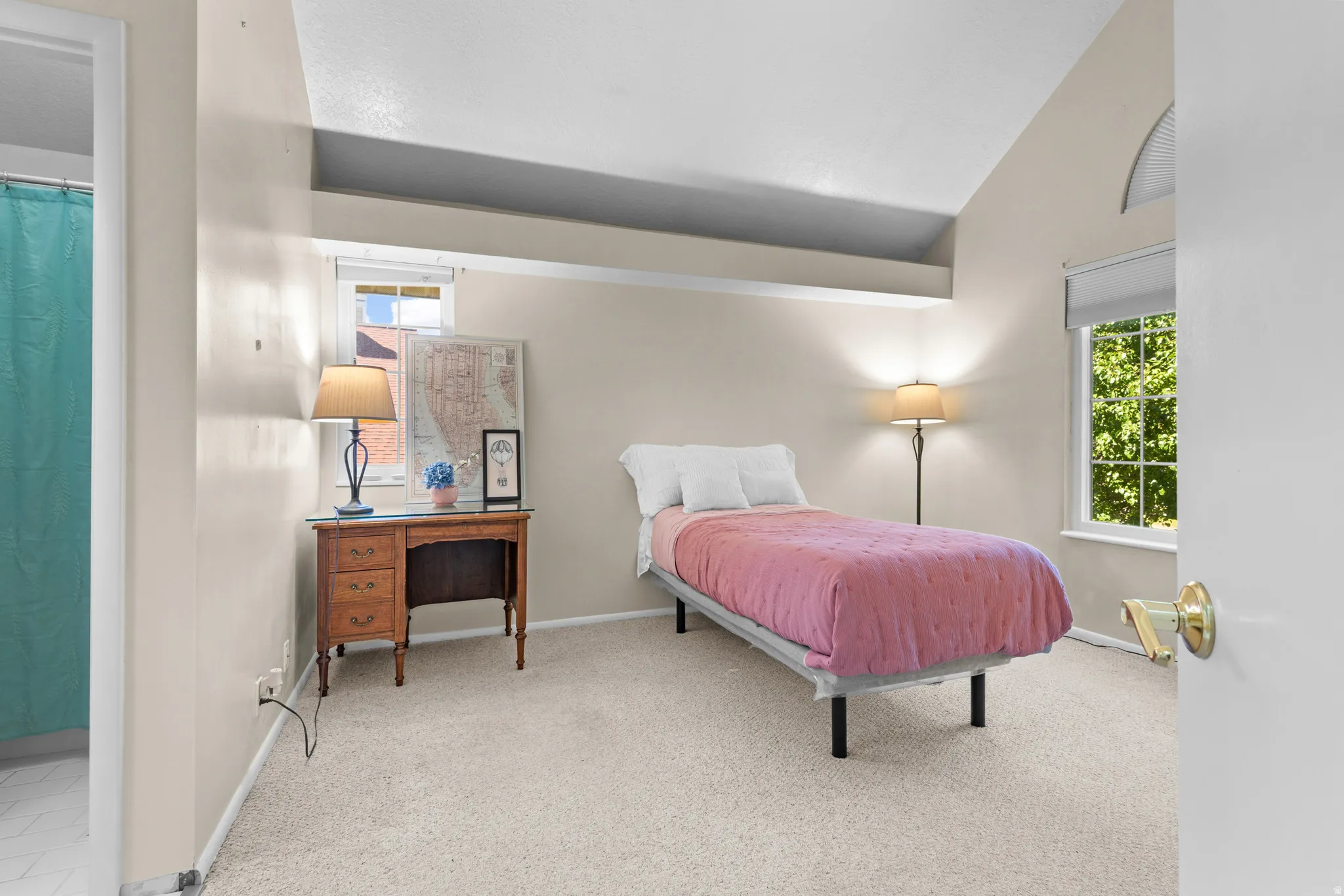 Vaulted ceilings with a high architectural shelf, soft neutral wall tones, and carpet flooring
