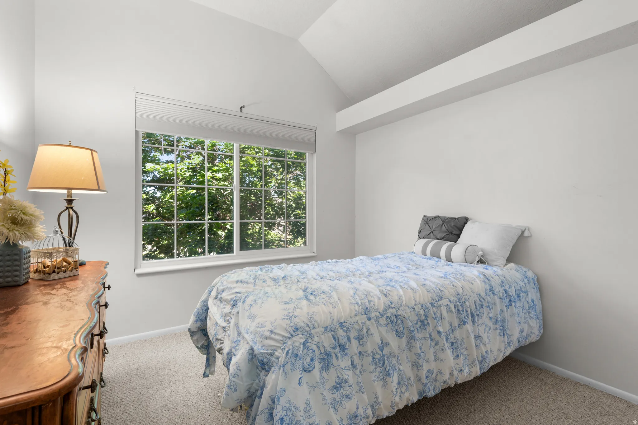 Room featuring a vaulted ceiling with exposed beam, a grid-pattern window, and neutral carpet flooring