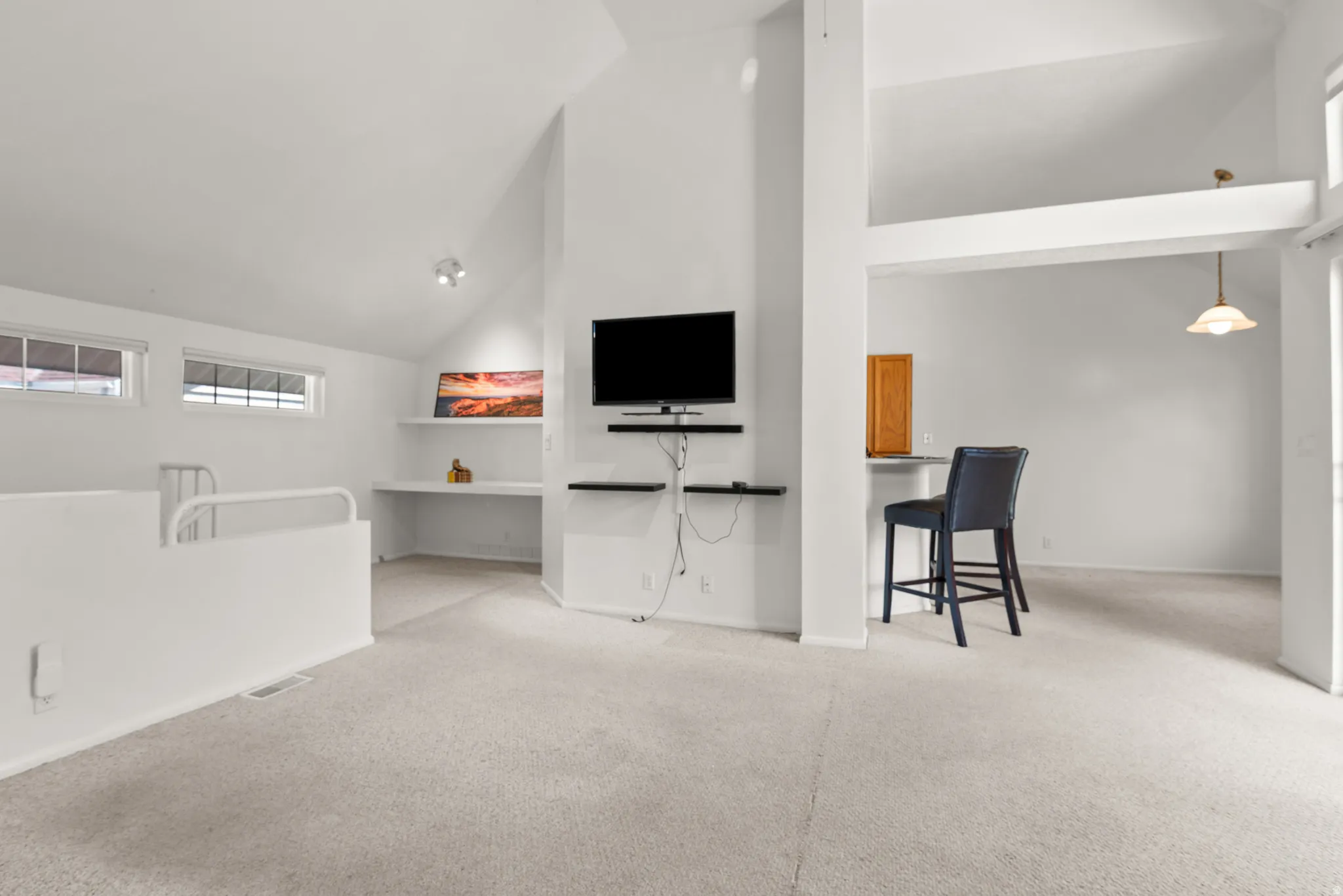 Carpeted loft space featuring an open railing, built-in desk with shelving, and recessed lighting