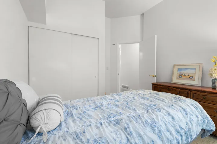 Bedroom featuring a built-in sliding door closet and a wall-mounted register