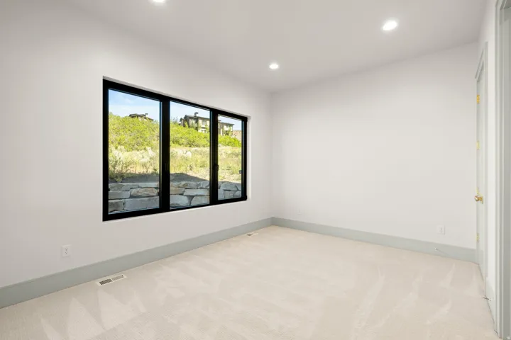 Room featuring a three-panel window with black frames, recessed ceiling lighting, light-colored carpeting, white walls, and gray baseboards