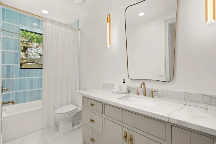 Contemporary bathroom featuring a vanity with a stone countertop, an undermount sink, and brass-finish fixtures