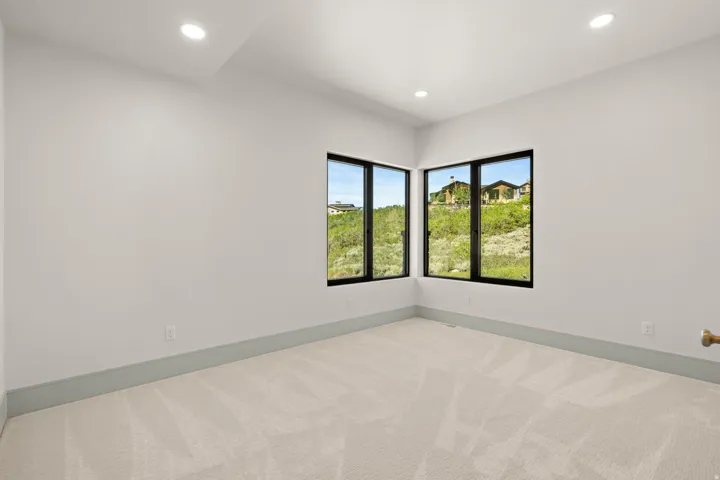 Room featuring corner windows with black frames, recessed lighting, neutral carpeting, and light gray baseboards