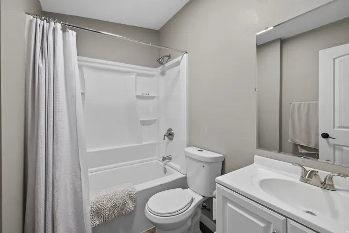 Bathroom featuring a white vanity with integrated sink, chrome faucet, and a large wall-mounted mirror