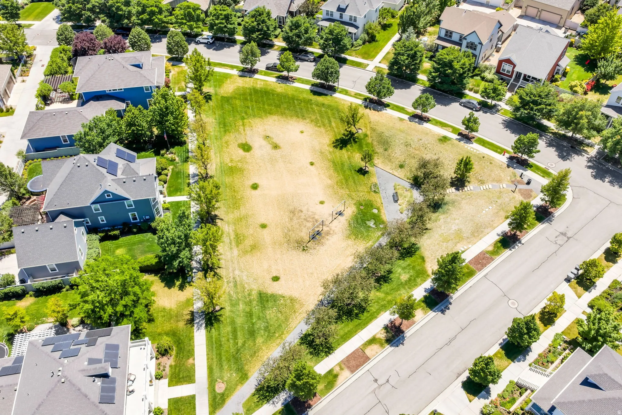 Expansive neighborhood green space featuring walking paths, mature trees, and landscaping