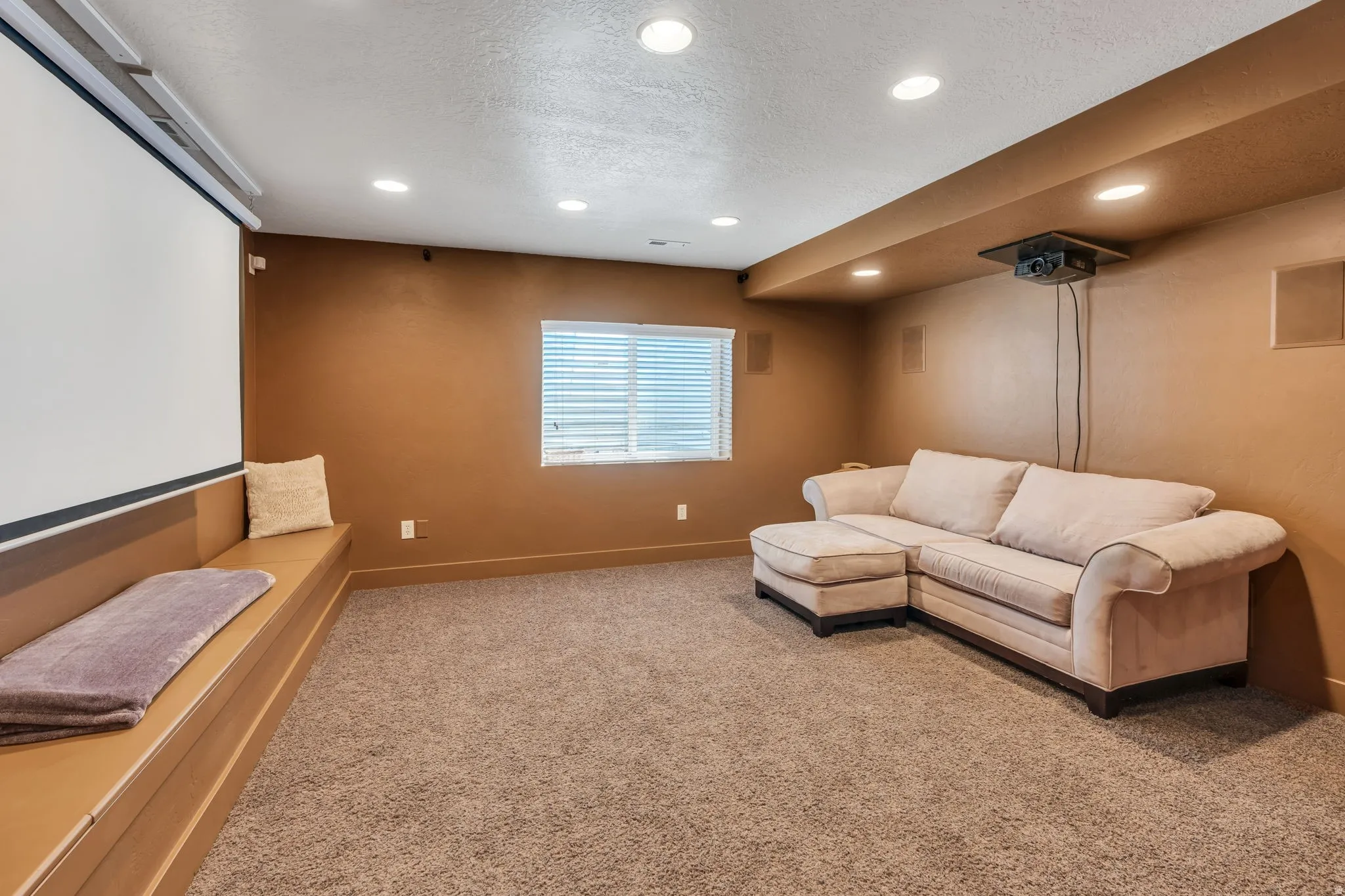 Entertainment room featuring a built-in projection screen, recessed lighting, and a window with horizontal blinds