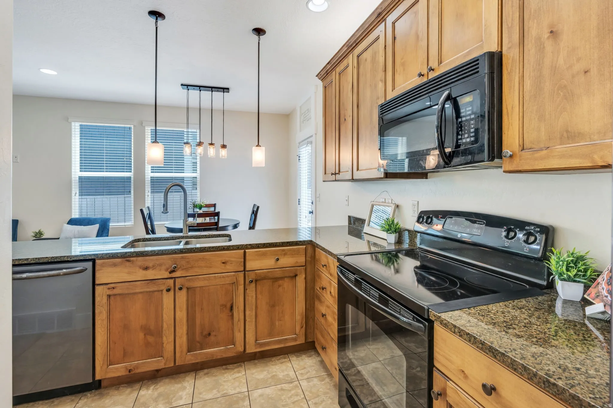 Open-concept kitchen featuring wood cabinetry, granite-finish countertops, and stainless-steel appliances
