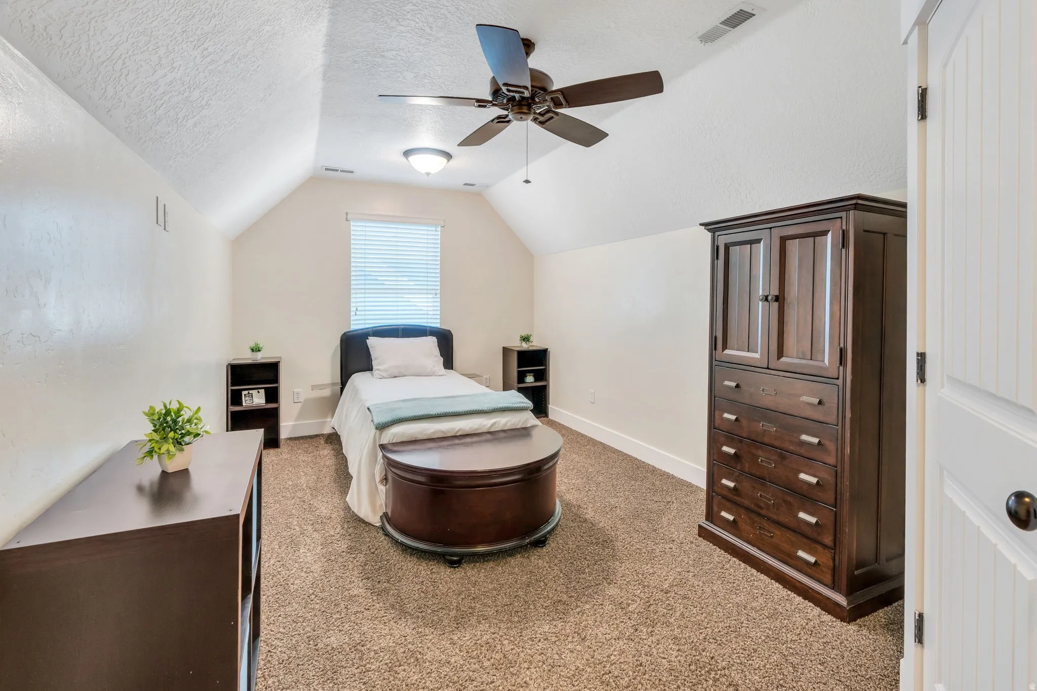 Carpeted room featuring a sloped ceiling and a ceiling fan with integrated lighting