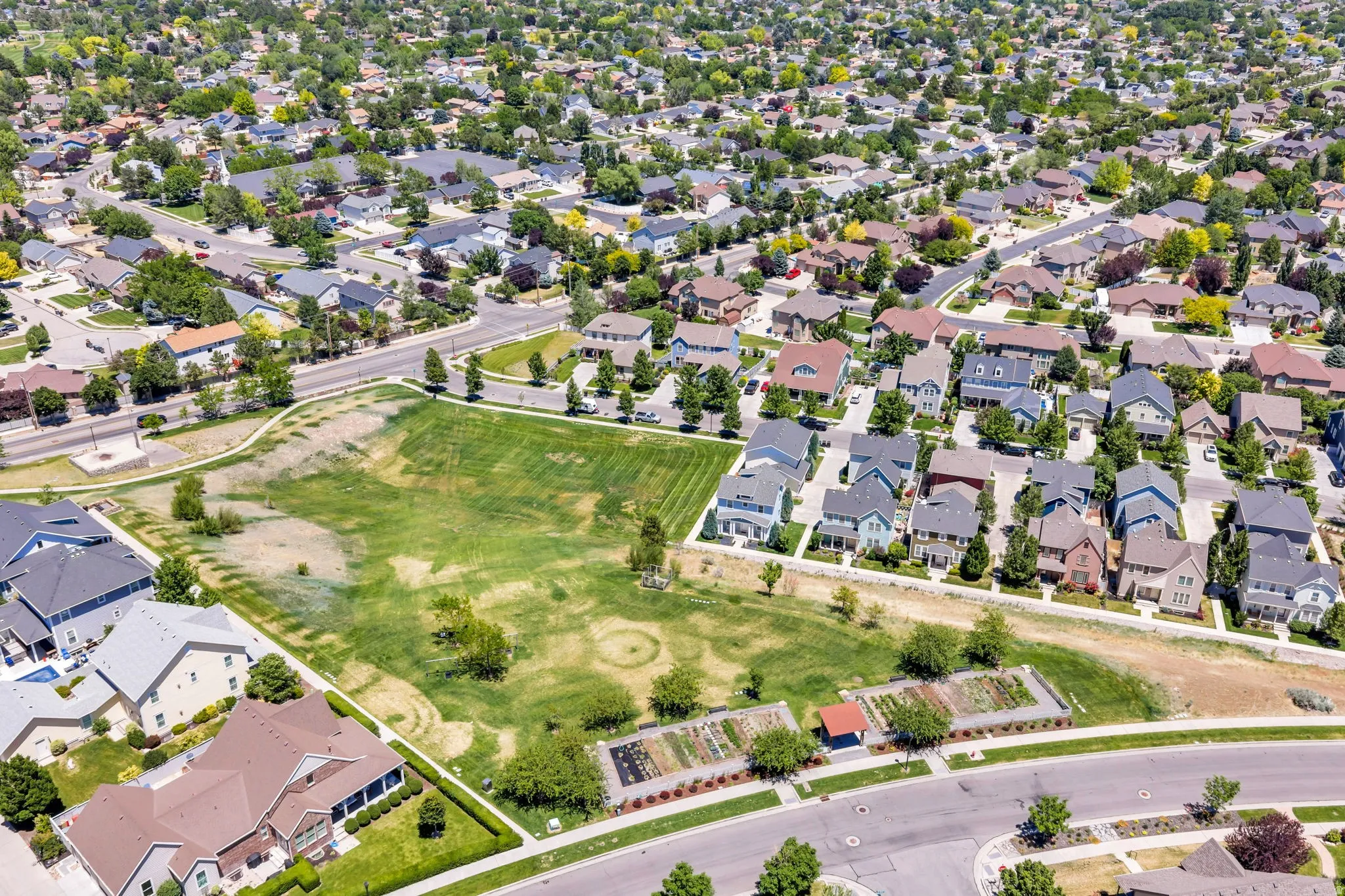 Expansive green space featuring a community garden and bordering residential properties