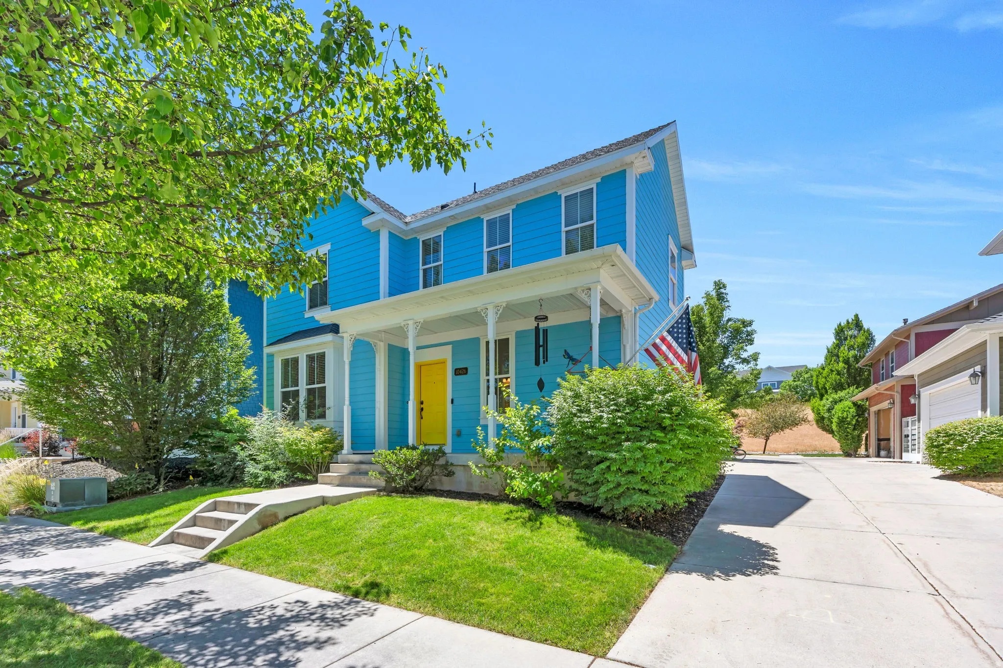 Two-story residence featuring vibrant blue siding, a white columned front porch, and a bright yellow entry door