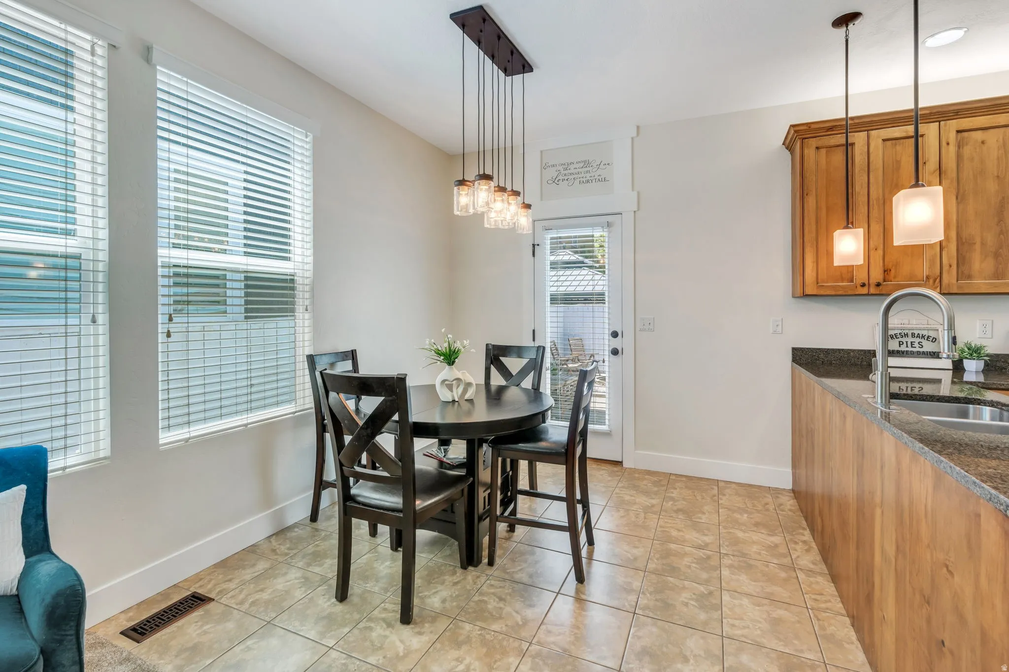 Dining area featuring ceramic tile flooring, two large windows with blinds, and a multi-light pendant fixture