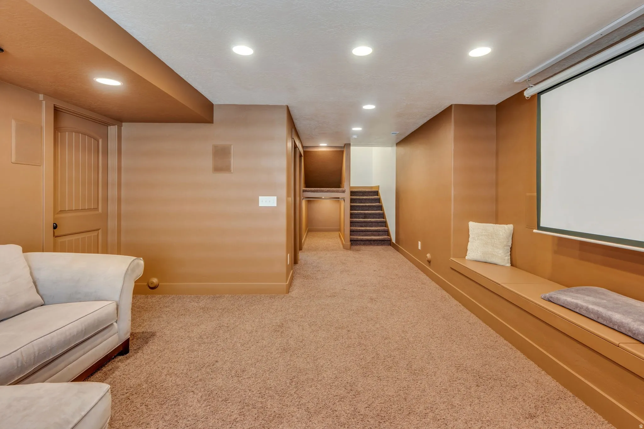Spacious room with recessed lighting, wall-to-wall carpeting, built-in projector screen, and custom built-in bench seating