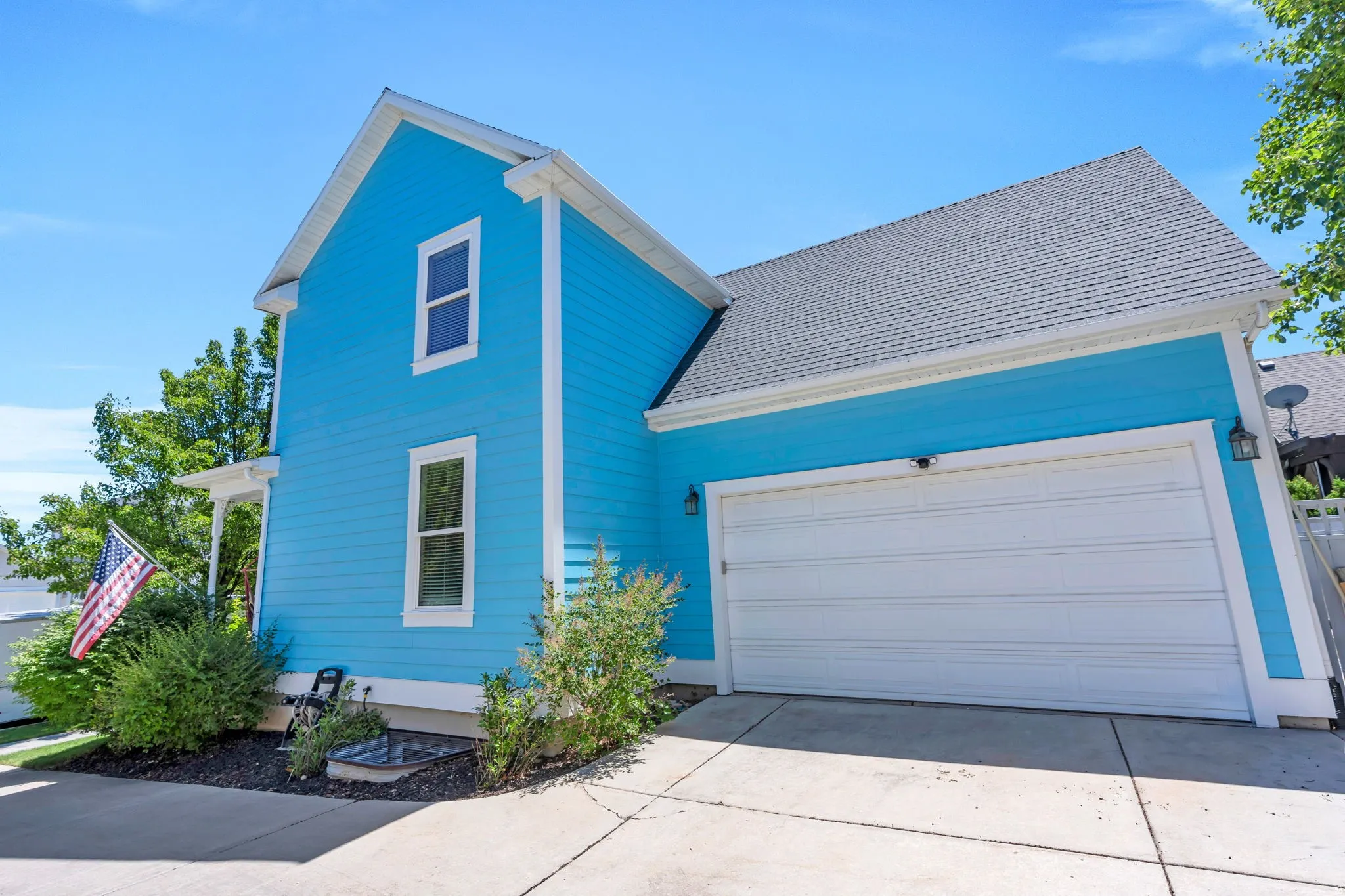 Vibrant blue siding exterior with white trim, featuring a single-car garage with a white panel door