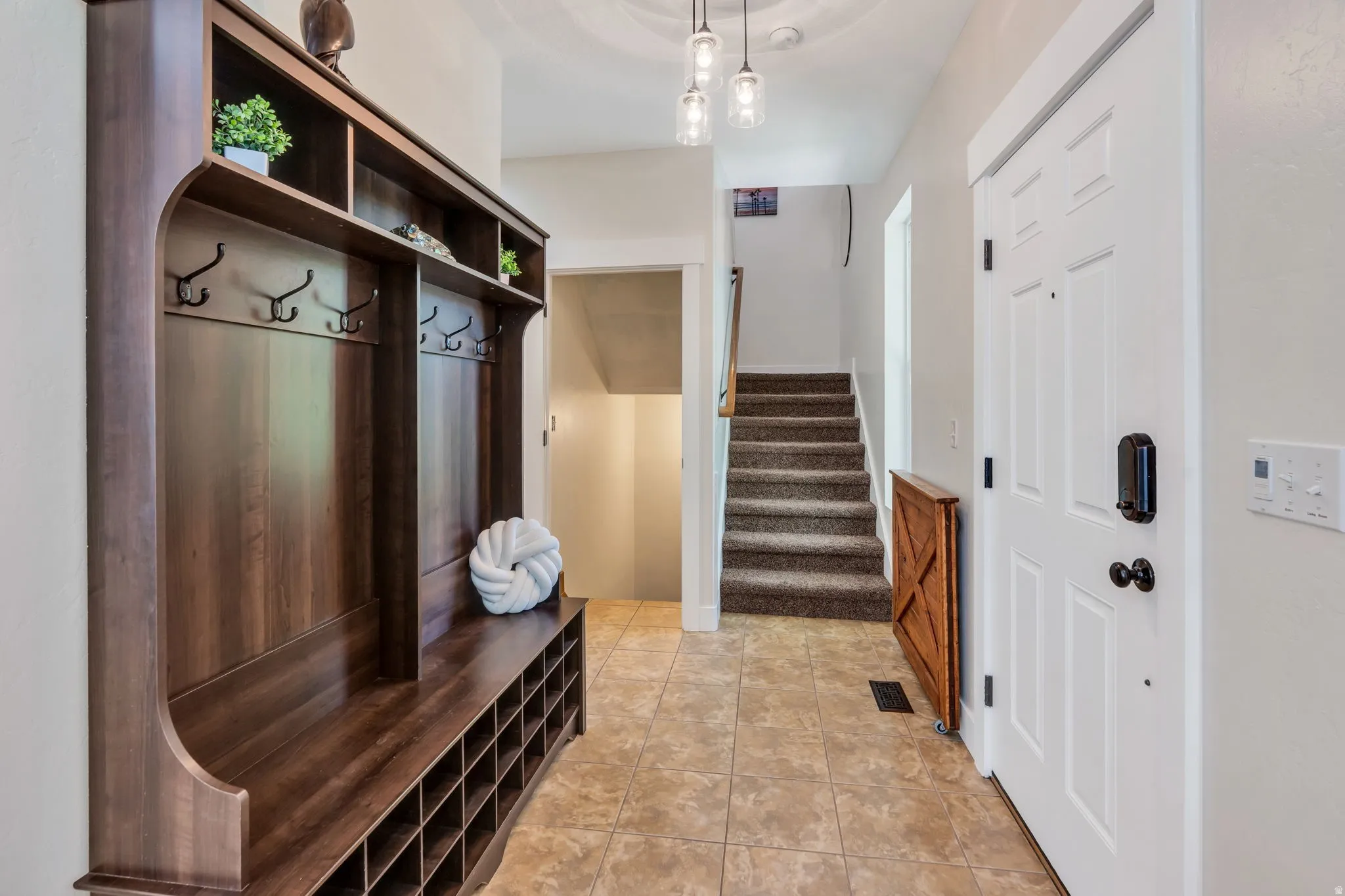 Foyer featuring a built-in wood-finish hall tree with bench seating, open shelving, and coat hooks