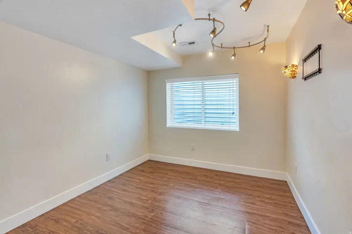 Room featuring wood-finish flooring, white baseboards, and neutral wall tones
