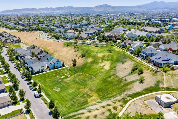 Expansive green space featuring a meandering walking path and distant mountain backdrops
