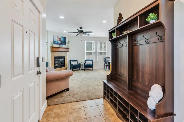 Entryway featuring a built-in dark wood-finish hall tree with storage cubbies and coat hooks, opening into a living area with a fireplace and ceiling fan