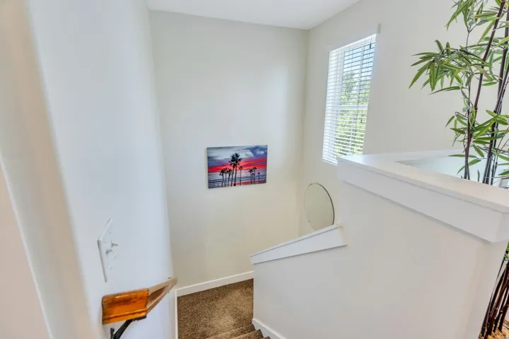 Stairwell featuring white walls, carpeting, and a window with horizontal blinds