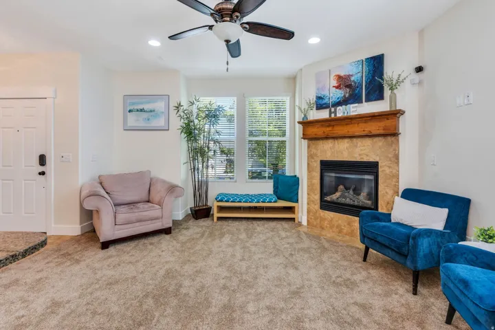 Spacious living area featuring a corner-set fireplace with a stone surround and wood mantel