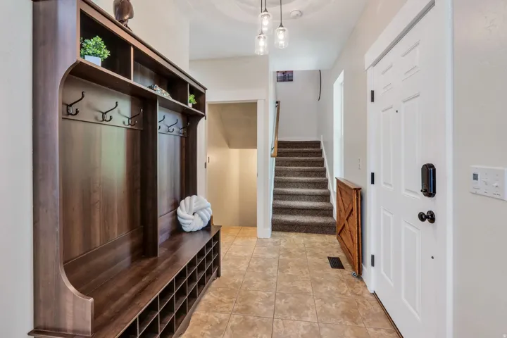 Foyer featuring a built-in wood-finish hall tree with bench seating, open shelving, and coat hooks