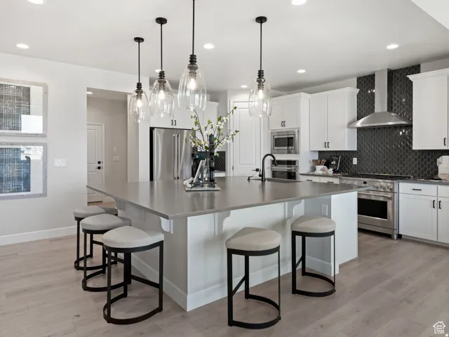 Spacious kitchen featuring a large central island with seating, white shaker cabinetry, stainless steel appliances, and a unique dark tile backsplash