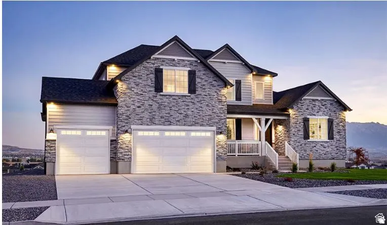 Two-story residence featuring stone and siding exterior, a covered front porch with white railing, and a two-car garage with individual doors