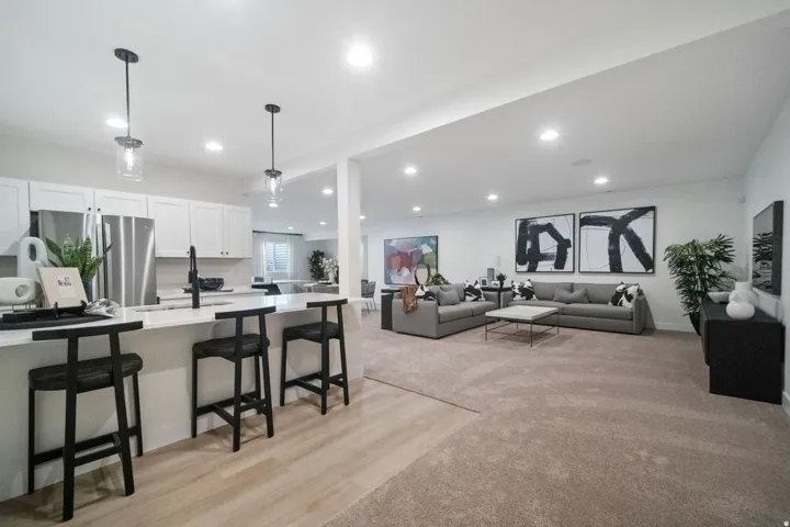 Open-concept living space featuring a modern kitchen with a large island, white cabinetry, and stainless steel appliances