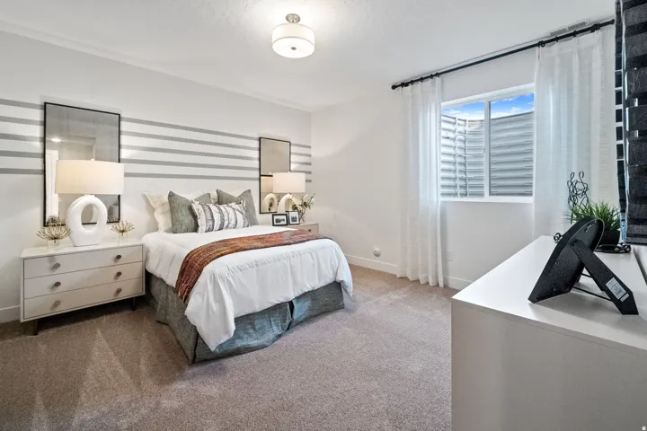 Carpeted bedroom featuring a window with a window well, a ceiling-mounted light fixture, and a decorative striped accent wall