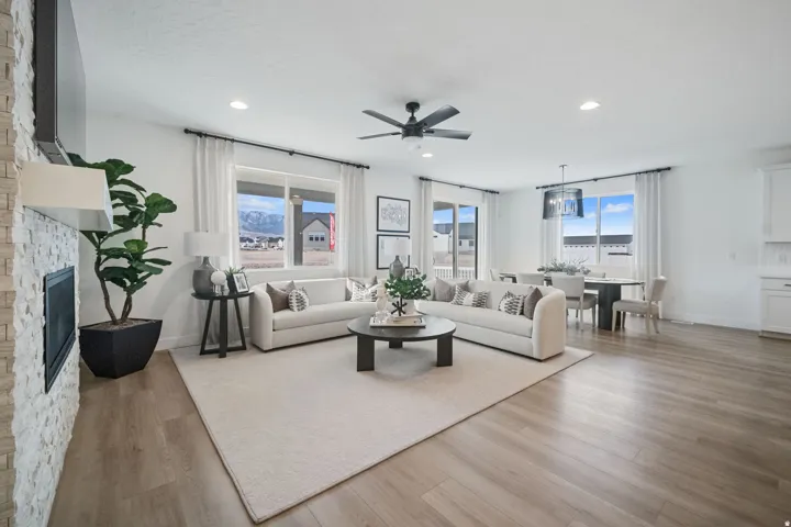 Open concept living area featuring wood-finish flooring, a stacked stone fireplace, and recessed lighting