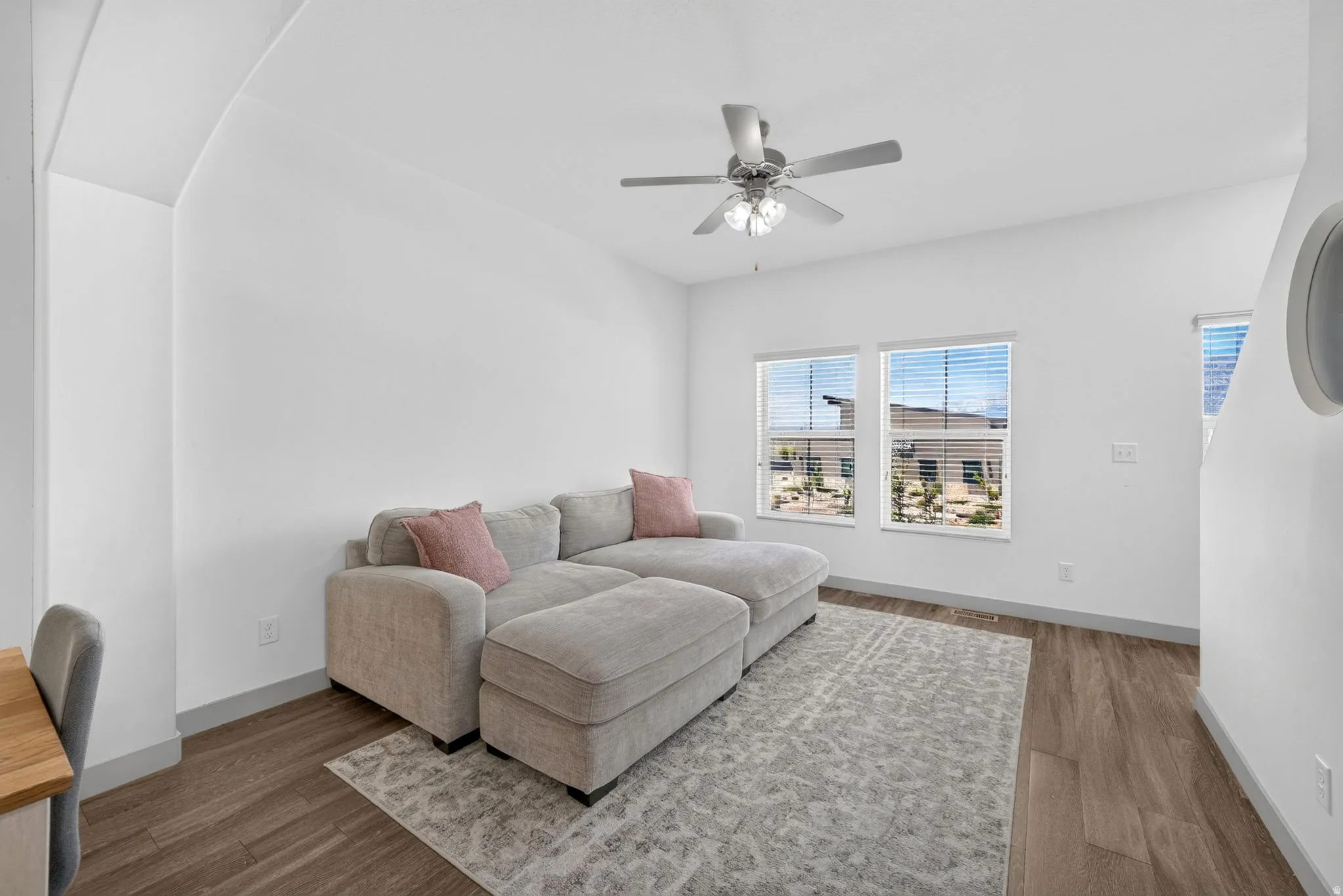 Bright interior space featuring wood-finish flooring, white walls, and a ceiling fan