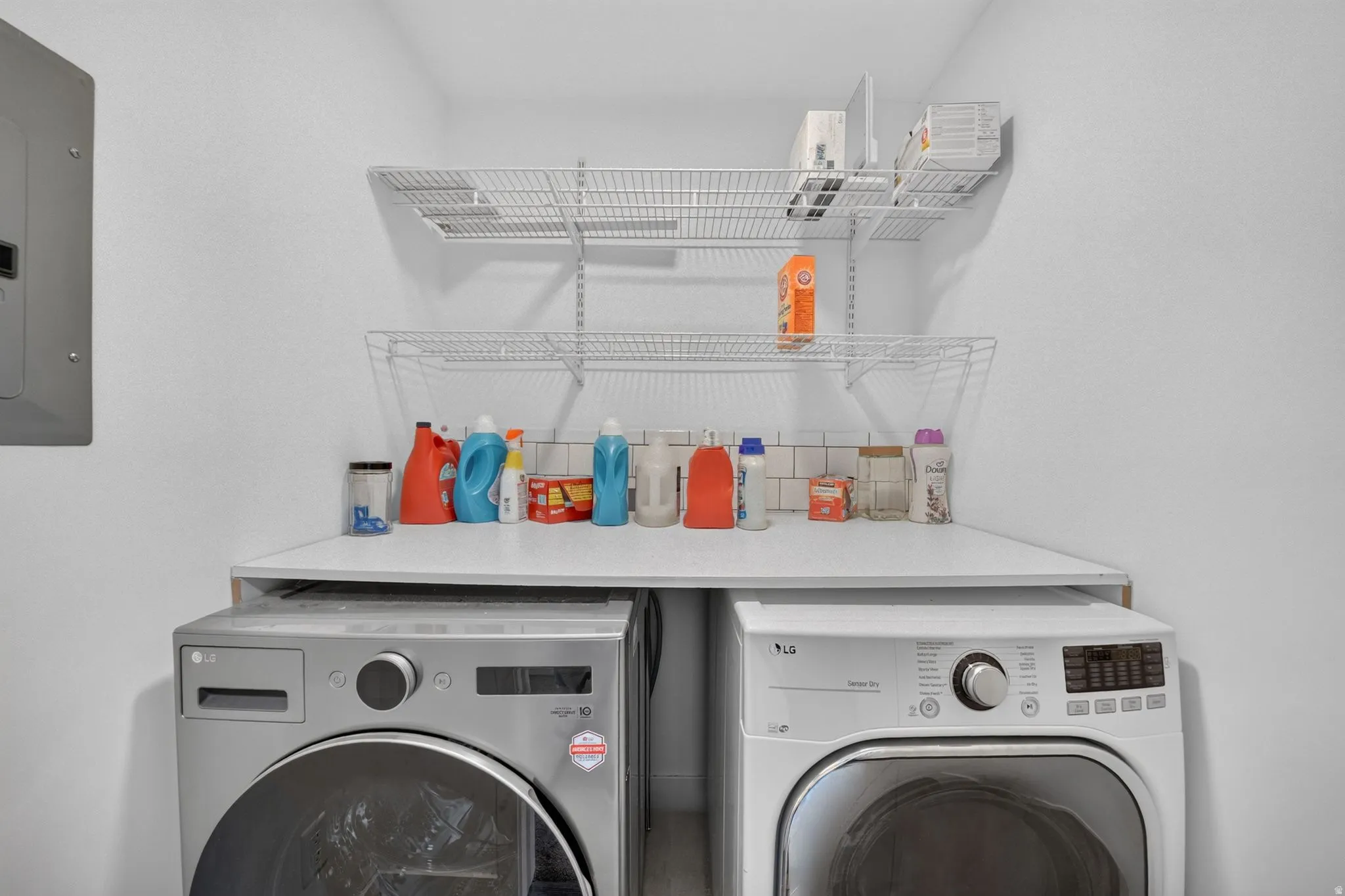 Dedicated laundry area featuring a countertop, subway tile backsplash, and two tiers of wire shelving